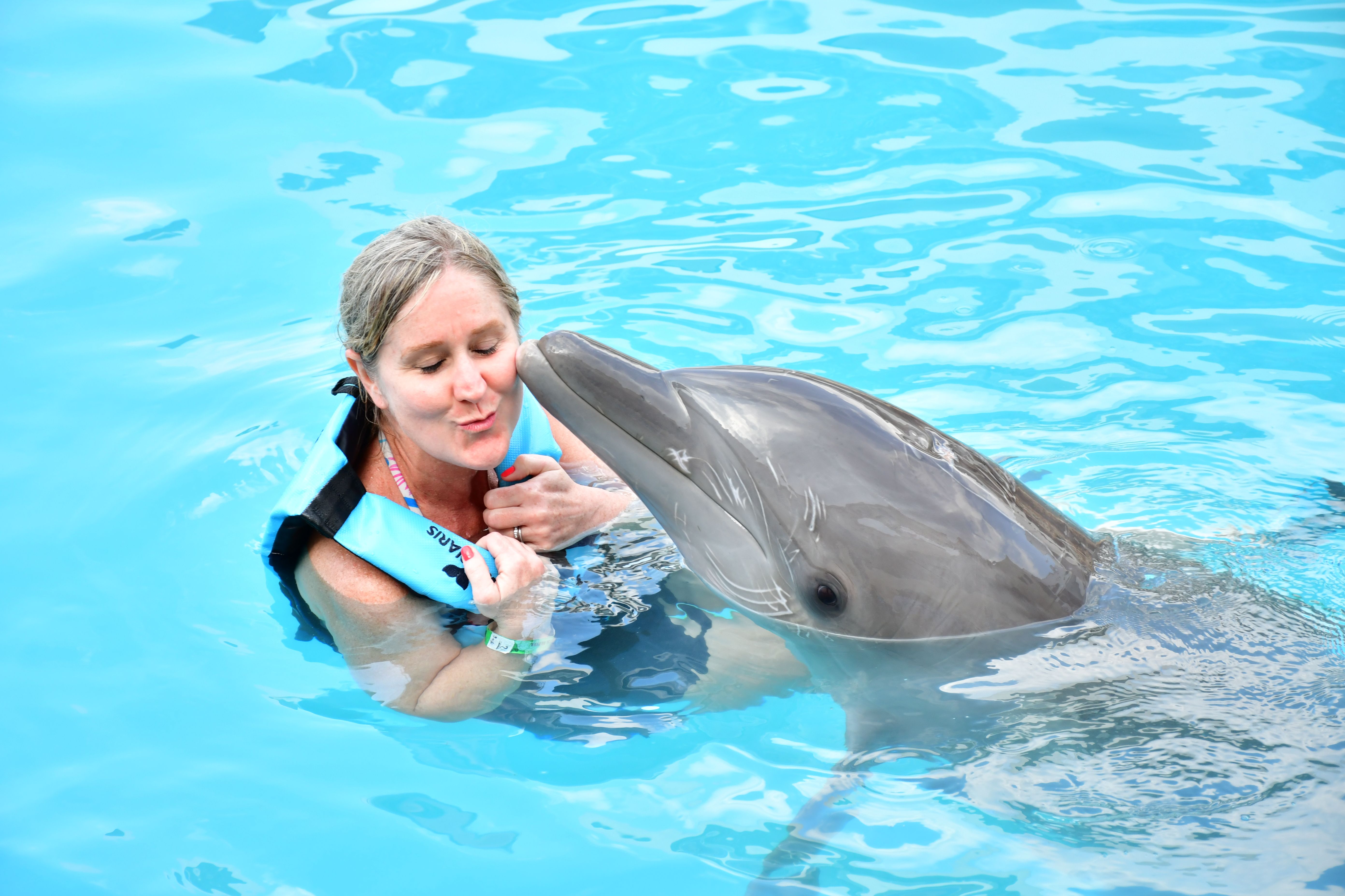 Dana in a pool giving a dolphin a kiss